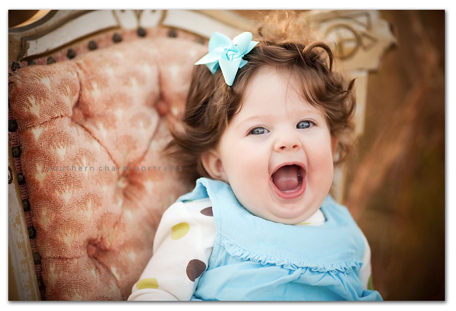 baby in antique victorian chair looks like a princess smiling big