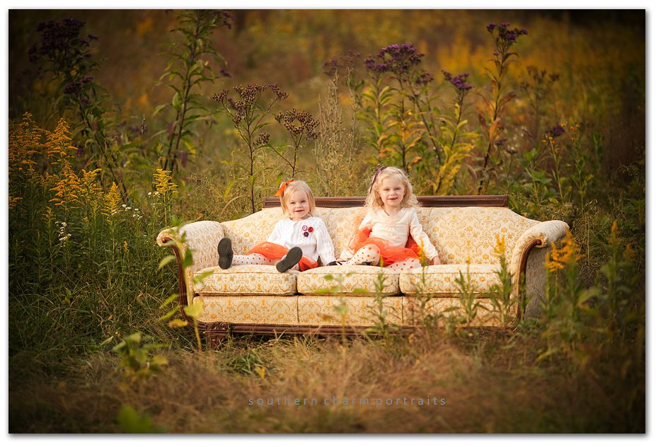 little sisters on vintage damask couch in grown up field with orange tuts