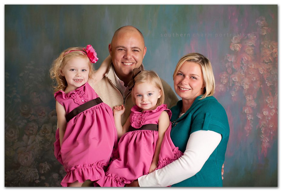 family having portraits made in photography studio with pink and blue background