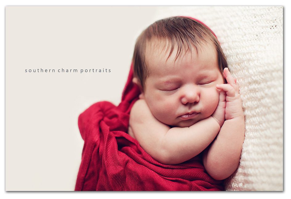 sleeping baby with folded hands with red sling