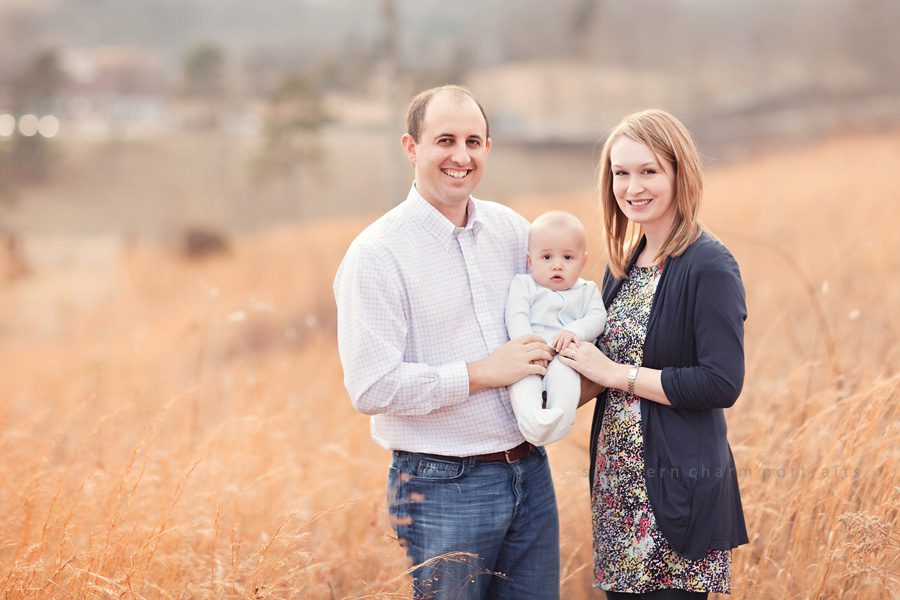 family of three in field with tall grass and complimentary outfits