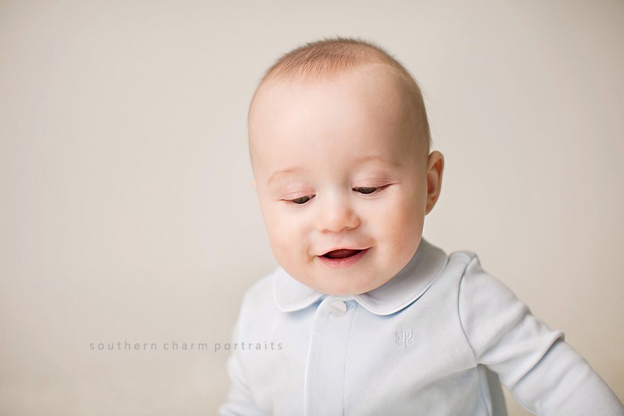 a sweet little grin from a six month old baby boy in photography studio