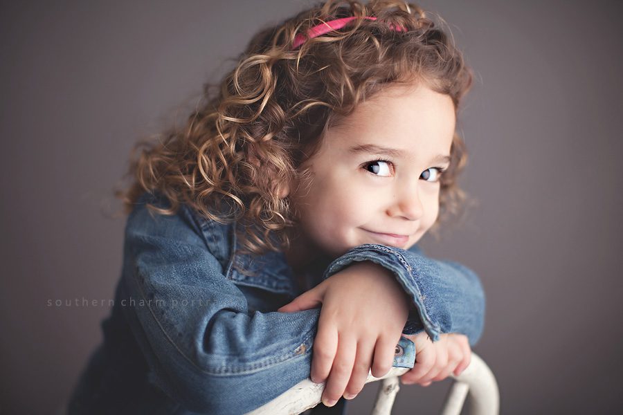 little girl in front of gray backdrop with cury q hair