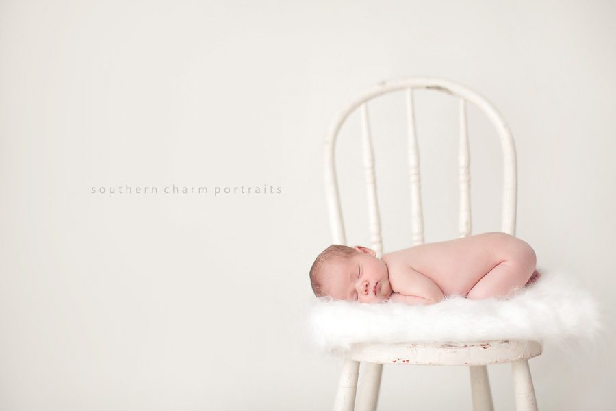 baby sleeping in chair on white blanet