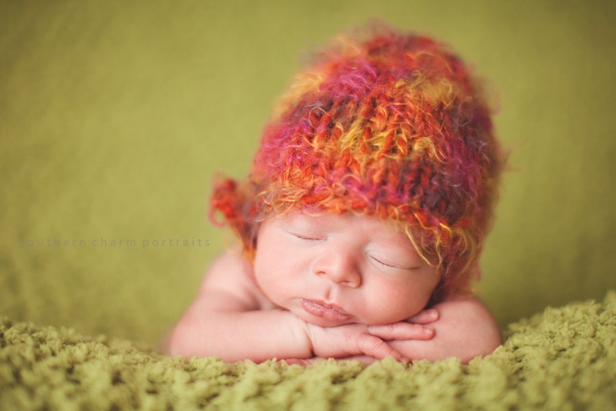 baby with knitted hat sleeping with head on arms