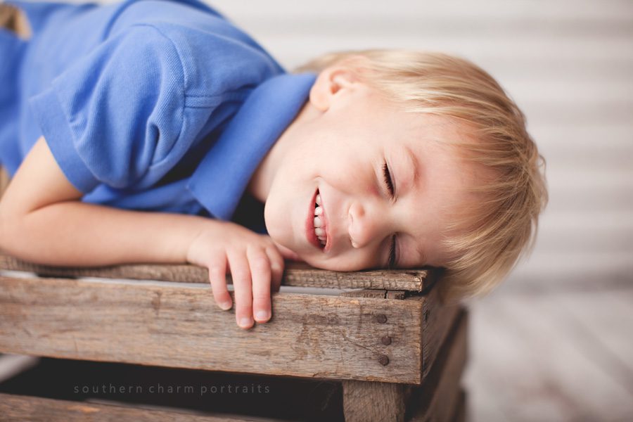 boy on crate smiling with eyes closed