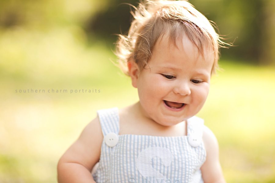 little boy on first birthday smiling and laughing in photo