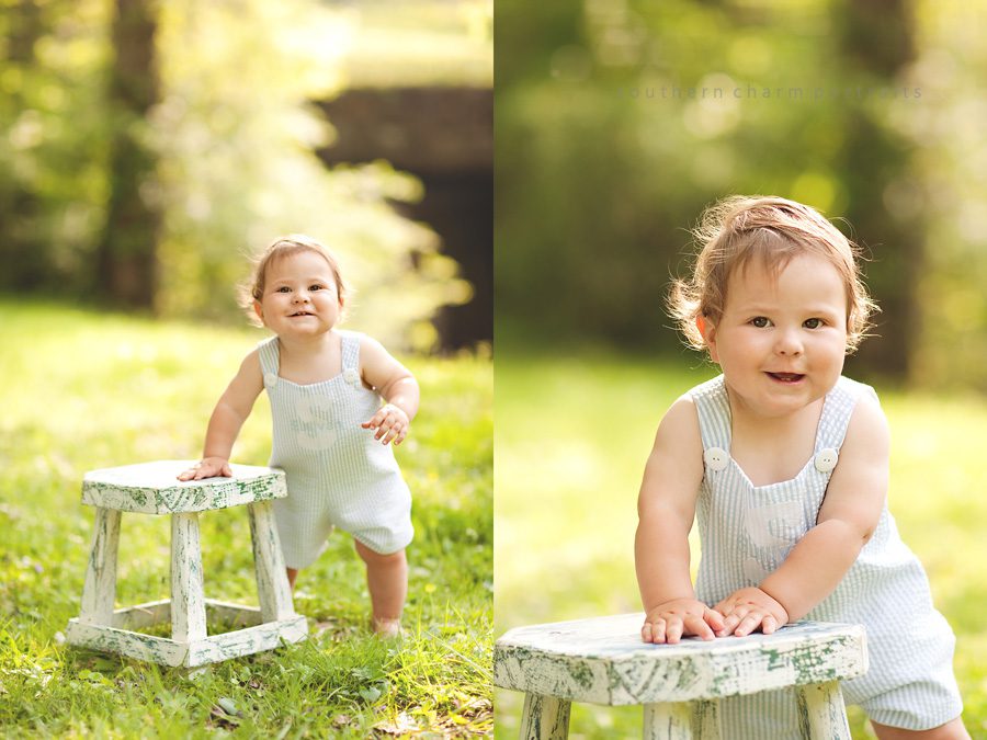 baby standing in grass holding onto stool