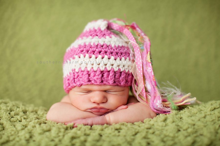 baby with ribbon hat sleeping with head on arms