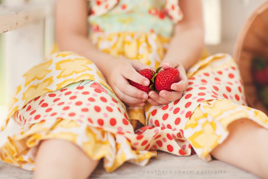 little girl holding strawberries in her hands