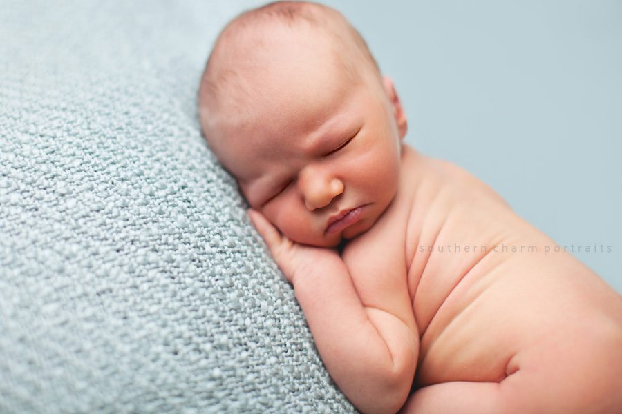 baby on blue blanket sleeping with hand under face